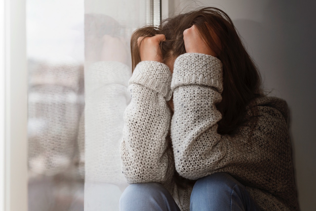 Depressive Frau vergräbt Gesicht in den Armen 