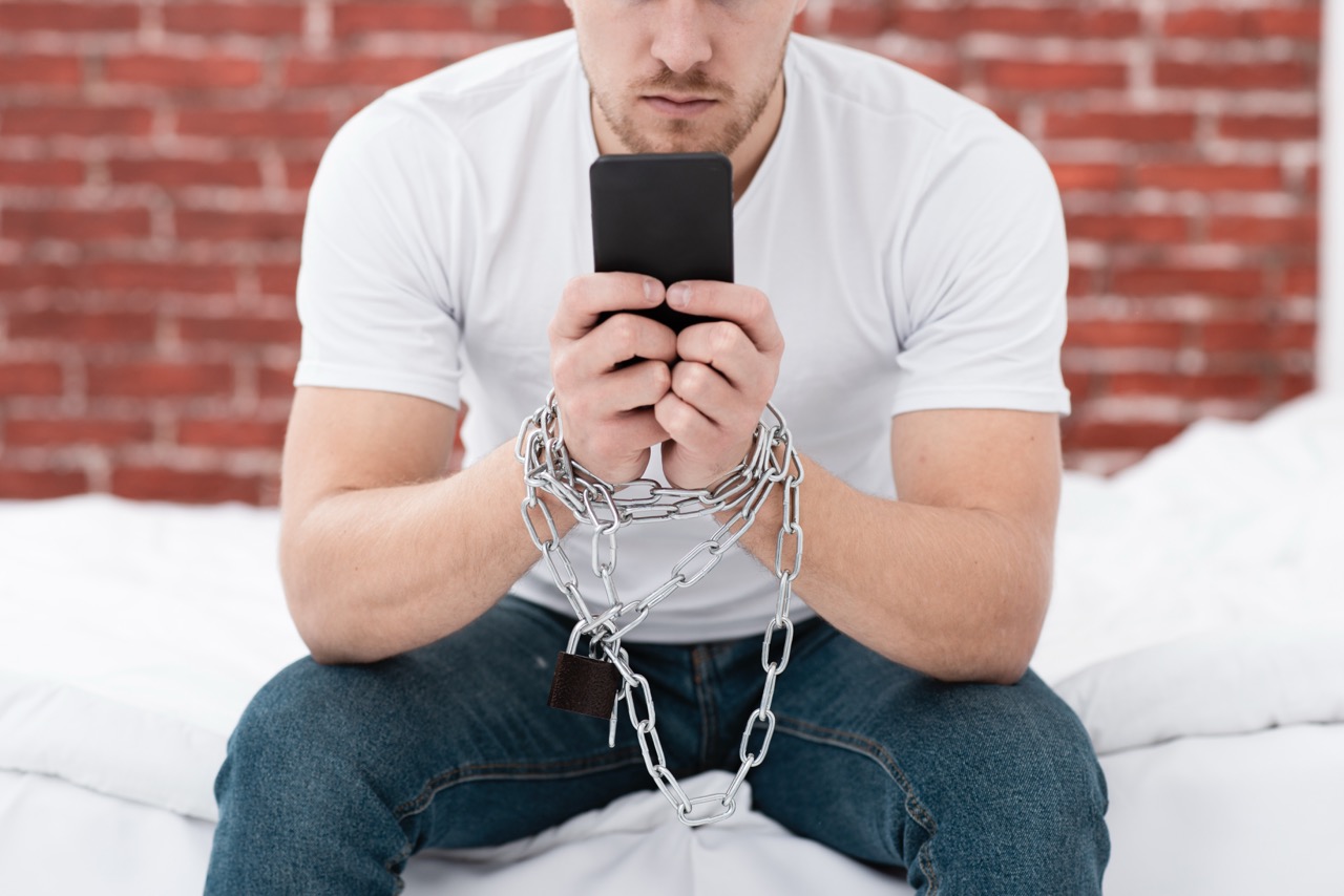 Mann ist ans Handy gefesselt digitale Reizüberflutung Symbolbild