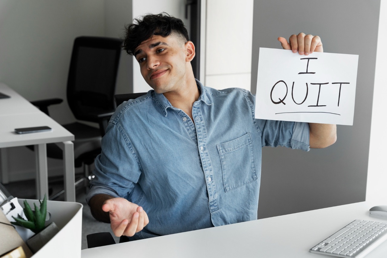 Junger Mann im Büro hebt Schild hoch auf dem Kündigung steht