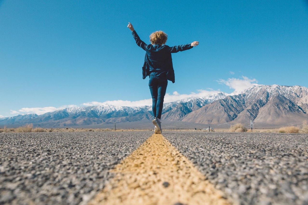 Frau Balanciert auf einer Straßenmarkierung Symbol für Balance zwischen Sicherheit und Wandlungsfähigkeit