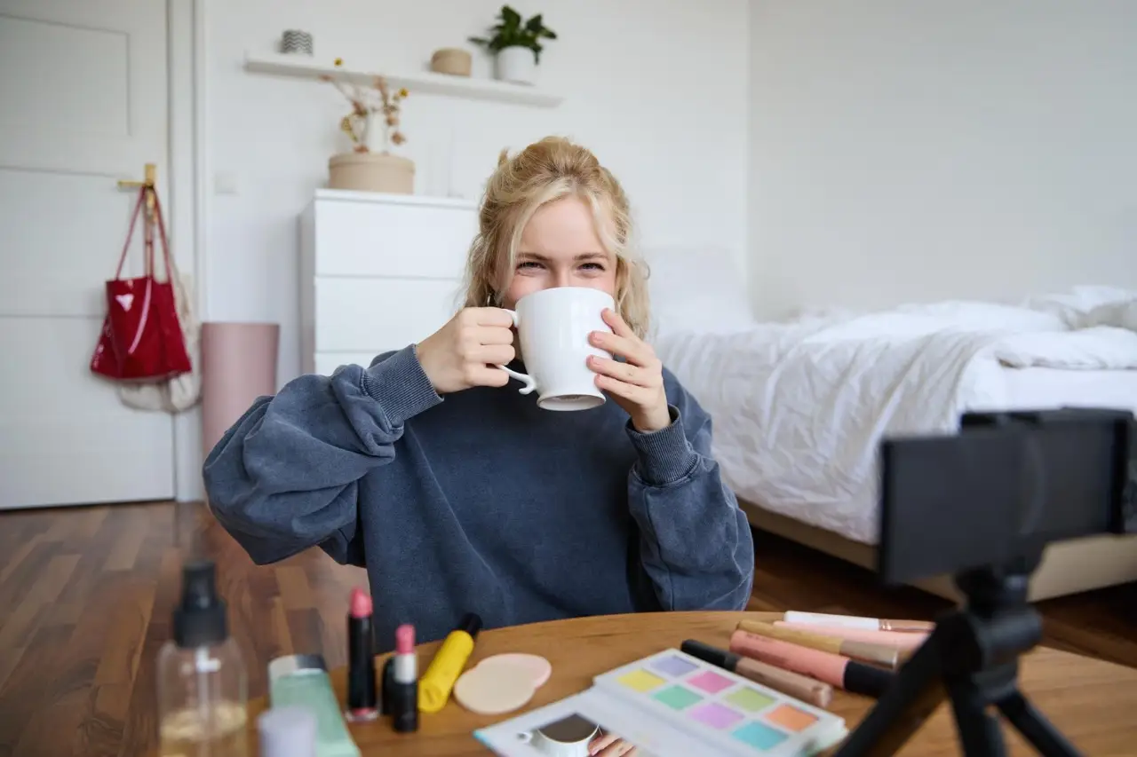 Frau hält eine Tasse an ihrem Schreibtisch mit Ringlicht