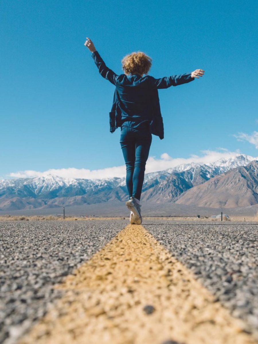 Frau Balanciert auf einer Straßenmarkierung Symbol für Balance zwischen Sicherheit und Wandlungsfähigkeit